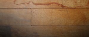 Discolored and damaged wood floorboards showing signs of moisture damage Vinyl flooring lifting from moisture-damaged subfloor.